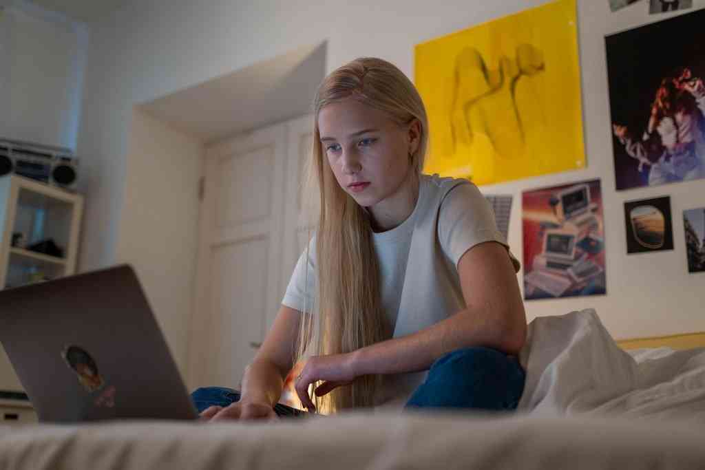 Девушка сидит на кровати с компьютером